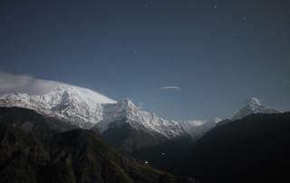 Snowy mountain peaks under a starry night sky.